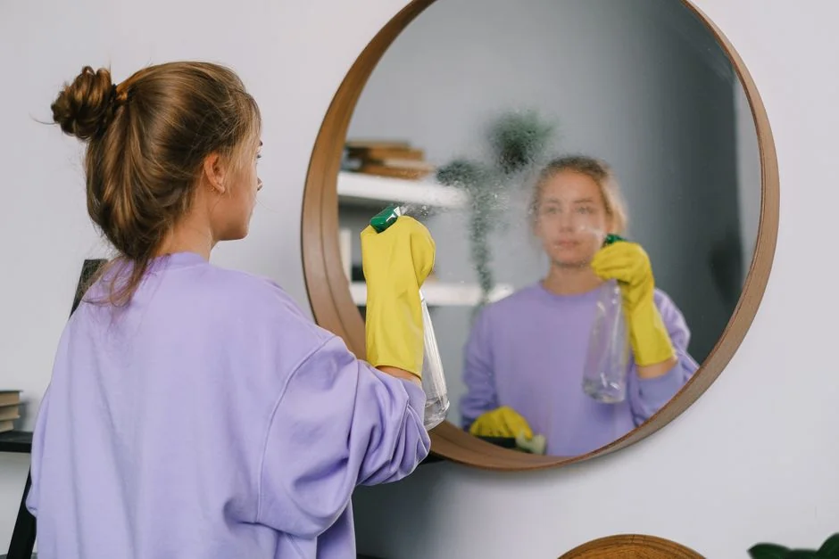 Un professionnel du nettoyage, équipé d’une tenue de protection, aspire le sol dans un salon moderne.